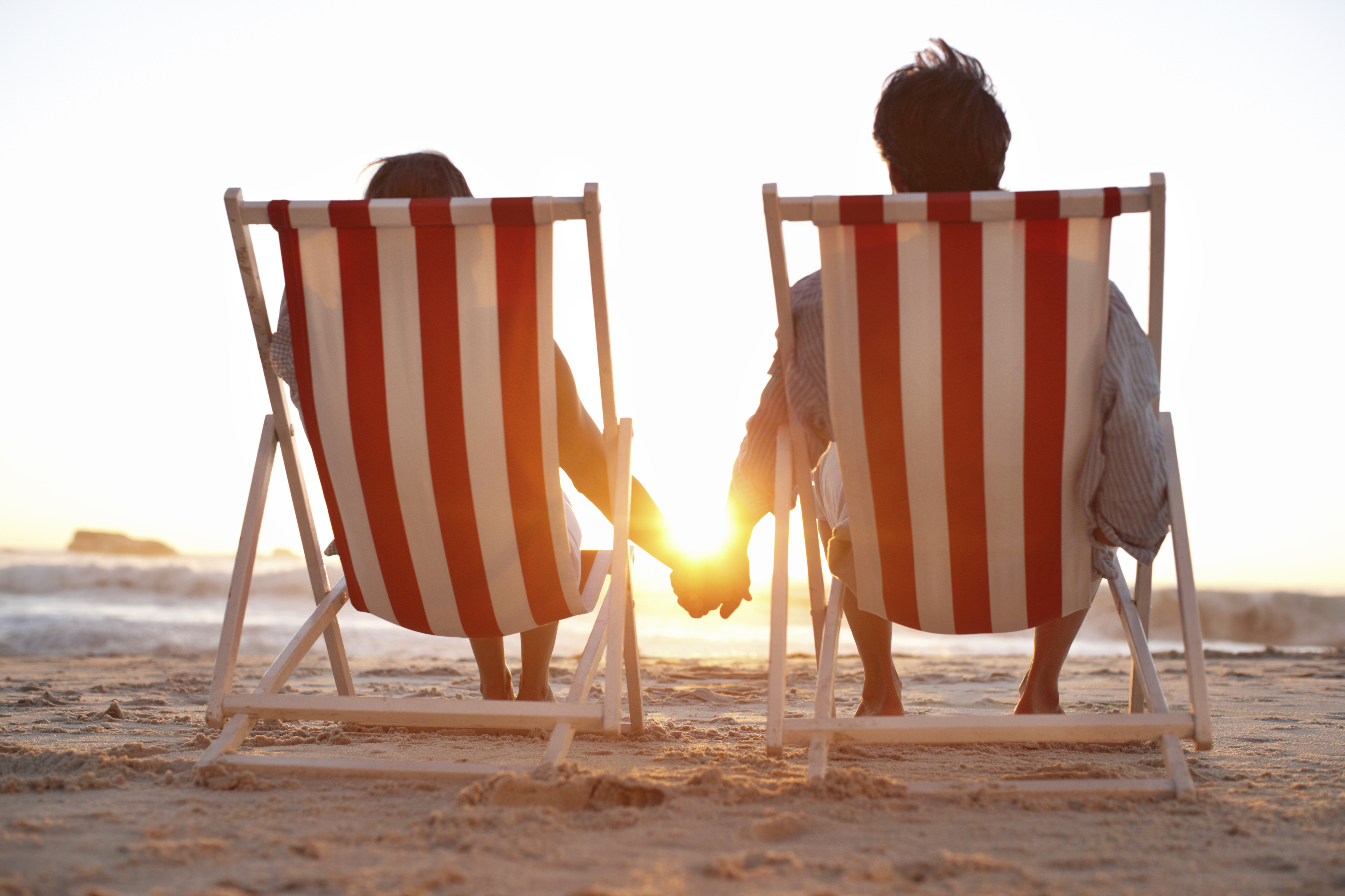 Couple dans transats sur la plage face au coucher de soleil